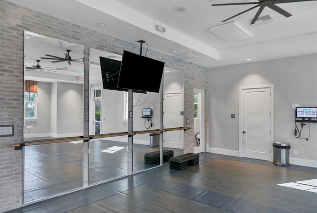 exercise room featuring ceiling fan and brick wall