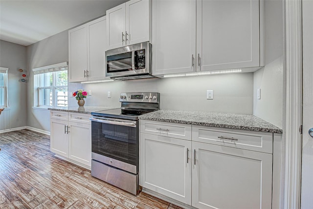 kitchen featuring appliances with stainless steel finishes, white cabinets, light stone counters, and light hardwood / wood-style flooring