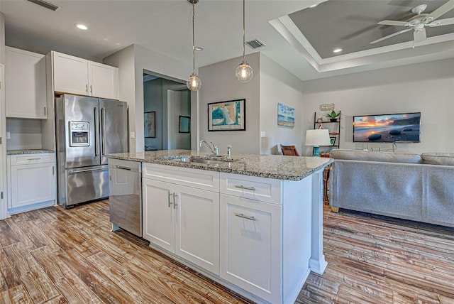 kitchen featuring sink, white cabinetry, hanging light fixtures, a center island with sink, and appliances with stainless steel finishes