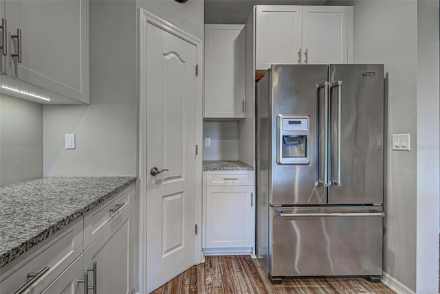 kitchen featuring light stone counters, hardwood / wood-style flooring, high end fridge, and white cabinets