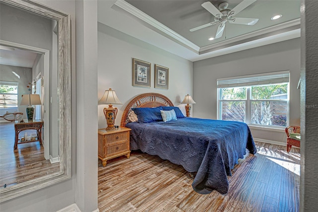 bedroom featuring crown molding, a tray ceiling, ceiling fan, and light hardwood / wood-style flooring