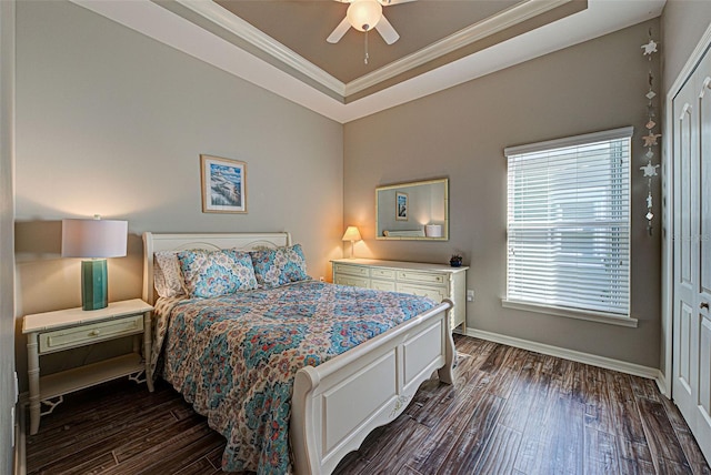 bedroom with dark wood-type flooring, ornamental molding, a raised ceiling, and ceiling fan