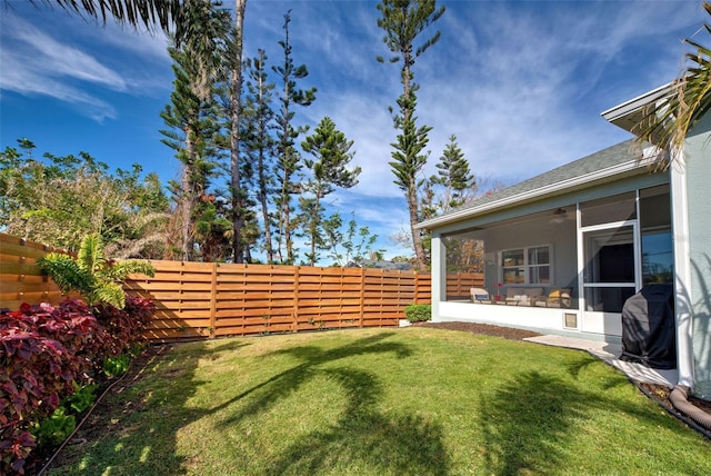 view of yard featuring a sunroom and ceiling fan