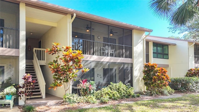 back of property featuring ceiling fan, stairs, and stucco siding