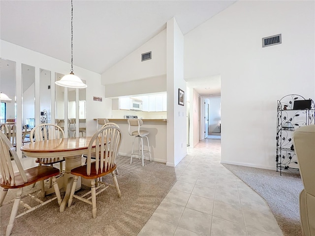 dining area with high vaulted ceiling, light colored carpet, visible vents, and light tile patterned flooring