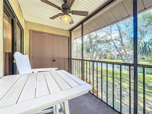 unfurnished sunroom featuring a water view and ceiling fan