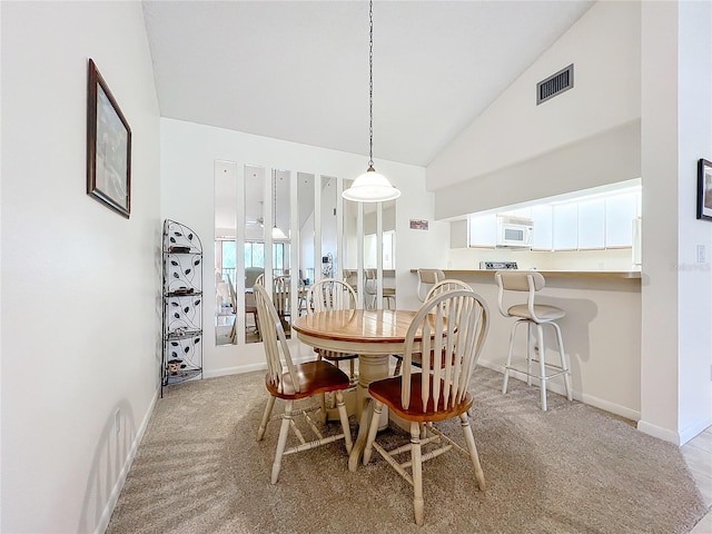 dining space with high vaulted ceiling, light colored carpet, visible vents, and baseboards