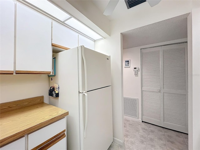 kitchen featuring visible vents, white cabinets, light countertops, and freestanding refrigerator