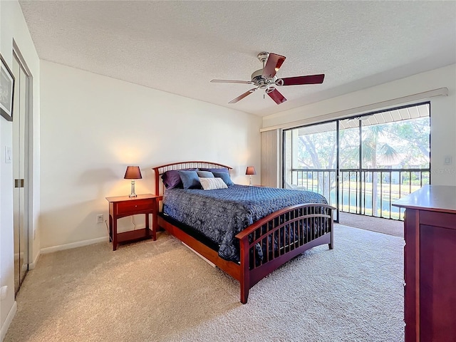 bedroom featuring a textured ceiling, light colored carpet, a ceiling fan, baseboards, and access to outside