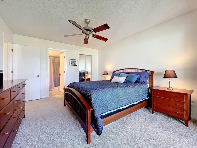 bedroom featuring light carpet, ceiling fan, and a textured ceiling