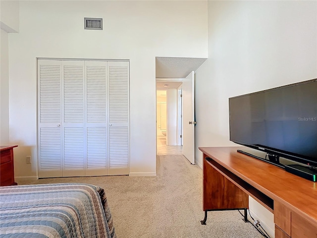 bedroom featuring light carpet, baseboards, visible vents, and a closet