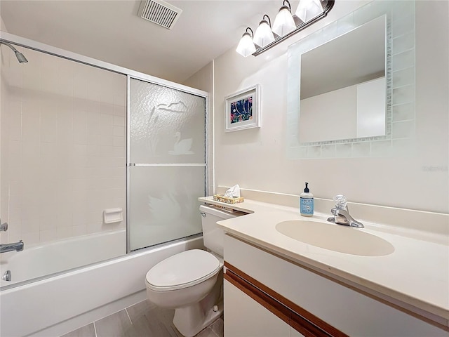 bathroom with visible vents, combined bath / shower with glass door, vanity, and toilet