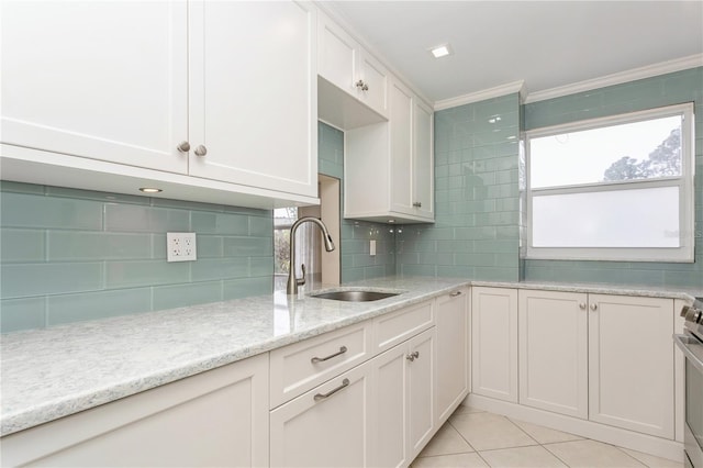 kitchen featuring white cabinetry, decorative backsplash, light tile patterned flooring, light stone countertops, and sink