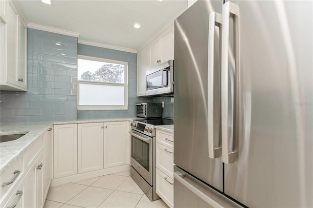 kitchen featuring crown molding, white cabinetry, stainless steel appliances, light tile patterned floors, and light stone counters