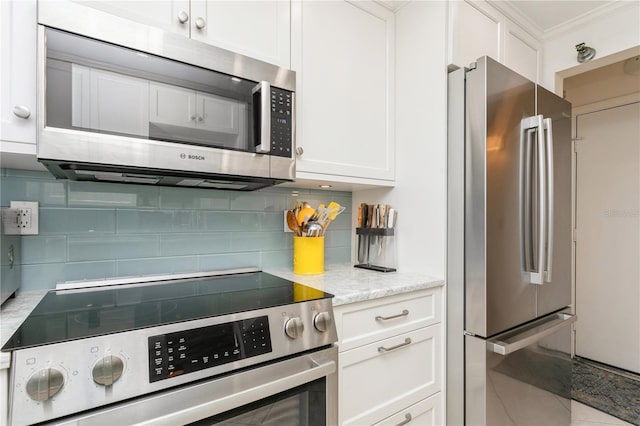 kitchen with light stone countertops, white cabinets, stainless steel appliances, backsplash, and crown molding