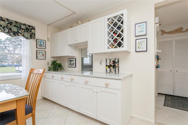 kitchen featuring light tile patterned floors, white cabinetry, and light stone countertops