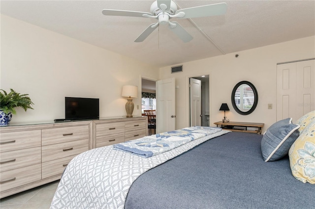 bedroom featuring ceiling fan, light tile patterned floors, and a closet