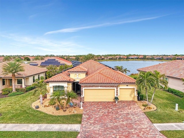 mediterranean / spanish house featuring decorative driveway, a tile roof, a water view, an attached garage, and a front yard