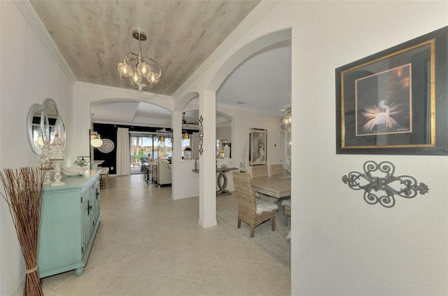 hall featuring ornamental molding, light tile patterned floors, and an inviting chandelier