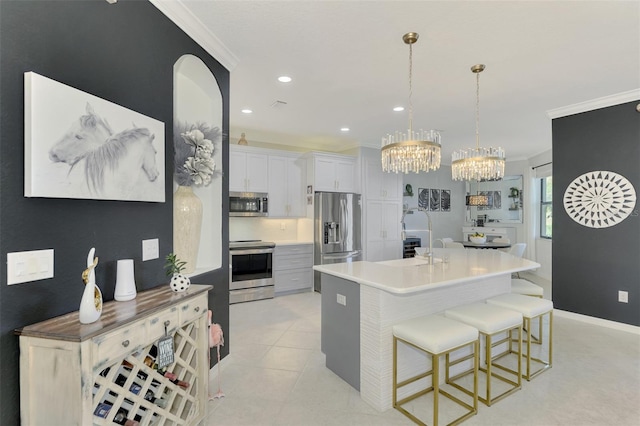 kitchen featuring white cabinets, hanging light fixtures, light tile patterned floors, stainless steel appliances, and crown molding