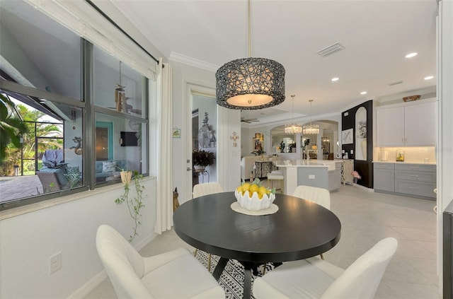 dining space with an inviting chandelier, light tile patterned floors, and crown molding