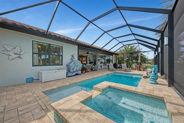 view of swimming pool featuring a grill, an in ground hot tub, ceiling fan, glass enclosure, and a patio area