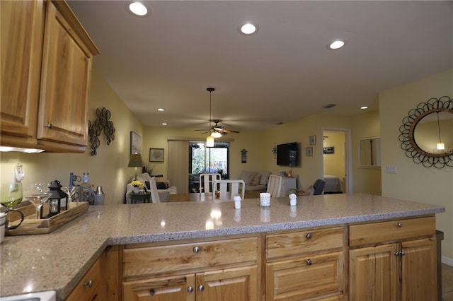 kitchen with ceiling fan, kitchen peninsula, and light stone countertops