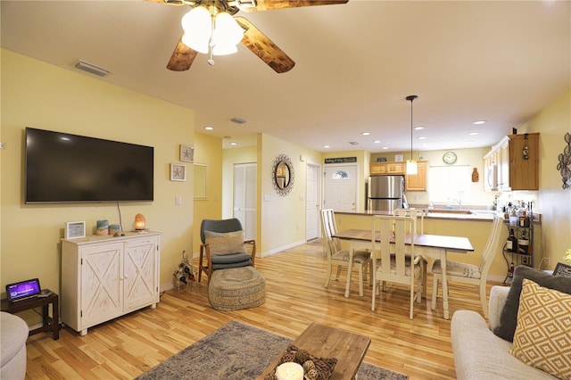 living room with light wood-type flooring and ceiling fan