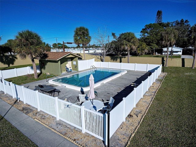 view of pool with a patio area, a yard, and an outdoor structure