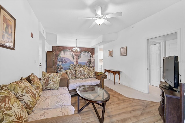 living room featuring ceiling fan with notable chandelier and light hardwood / wood-style flooring