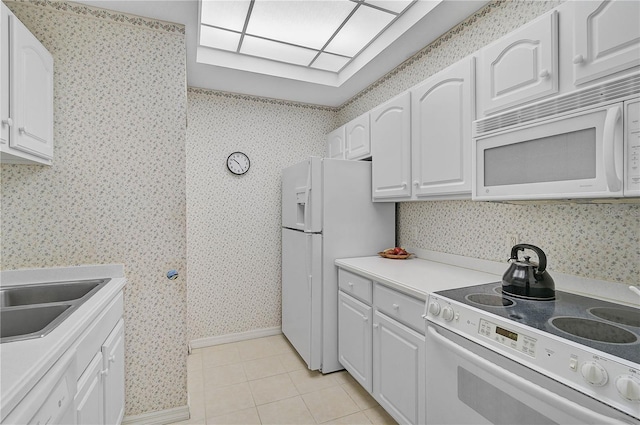 kitchen with light tile patterned floors, sink, white appliances, and white cabinetry