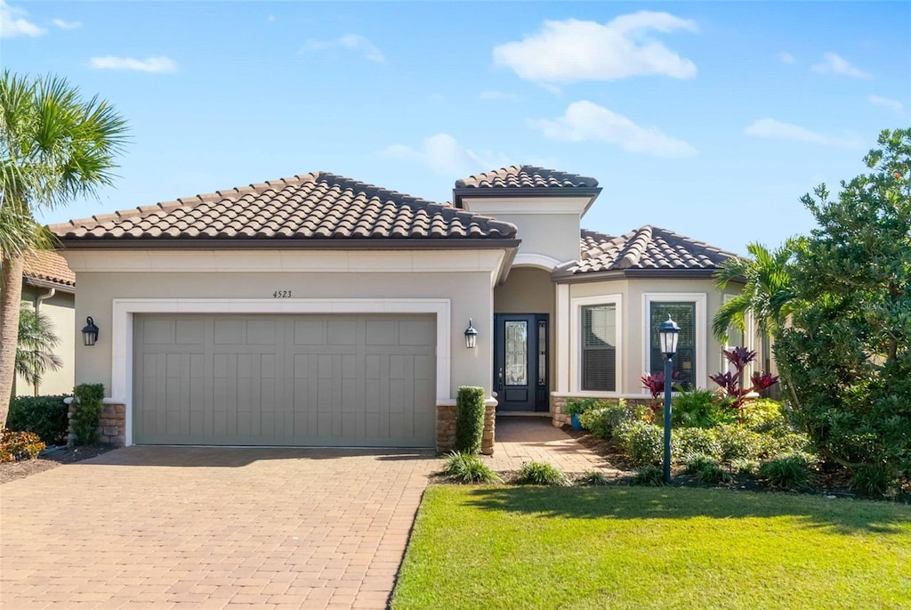 mediterranean / spanish house featuring a garage and a front lawn