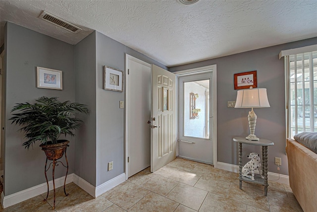 foyer entrance featuring light tile patterned flooring and a textured ceiling