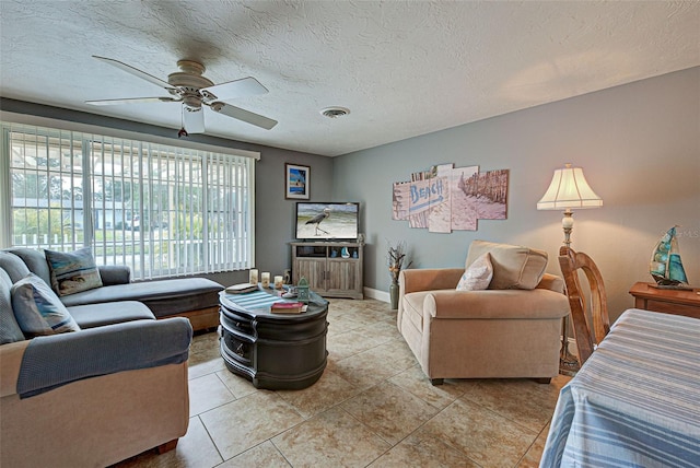 living room featuring ceiling fan, light tile patterned flooring, and a textured ceiling