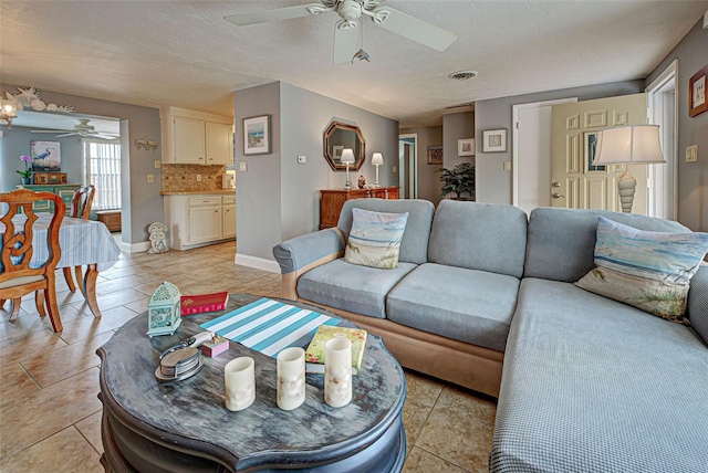 tiled living room featuring ceiling fan and a textured ceiling