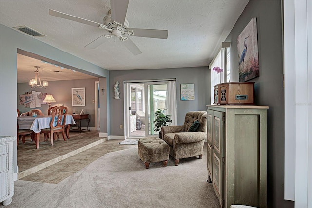 sitting room featuring ceiling fan with notable chandelier, a textured ceiling, and light carpet