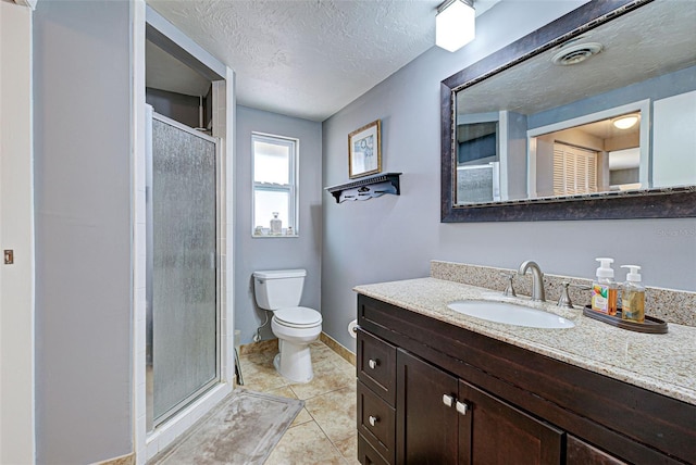 bathroom featuring toilet, vanity, a shower with door, and a textured ceiling