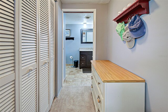 hall featuring a textured ceiling and light colored carpet