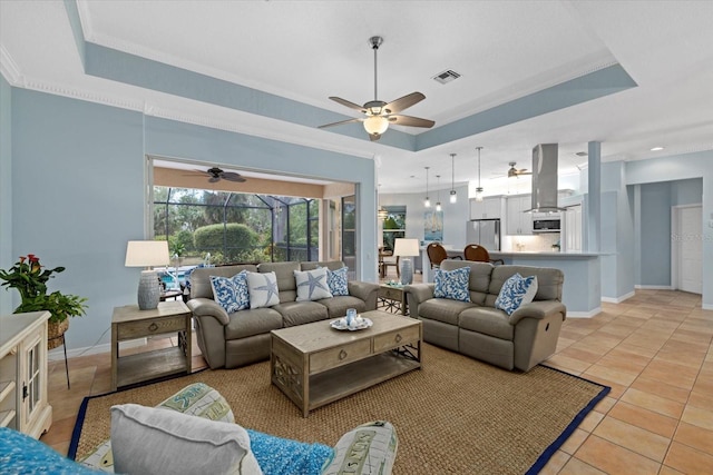 tiled living room with crown molding and a tray ceiling