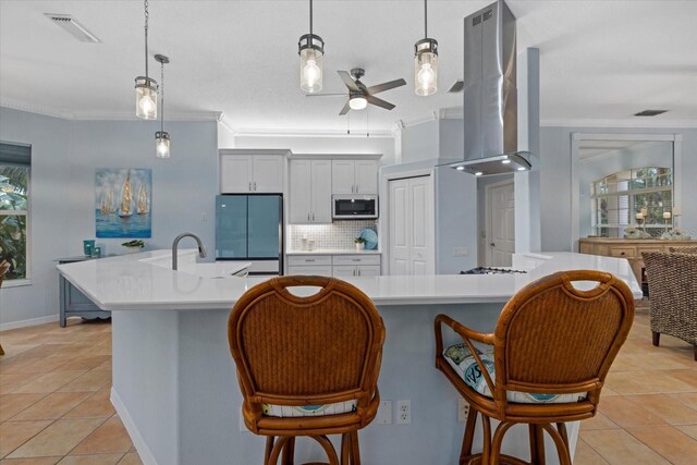 kitchen with refrigerator, island exhaust hood, decorative backsplash, and hanging light fixtures