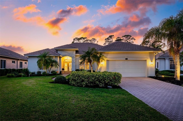 mediterranean / spanish-style home featuring a garage and a lawn