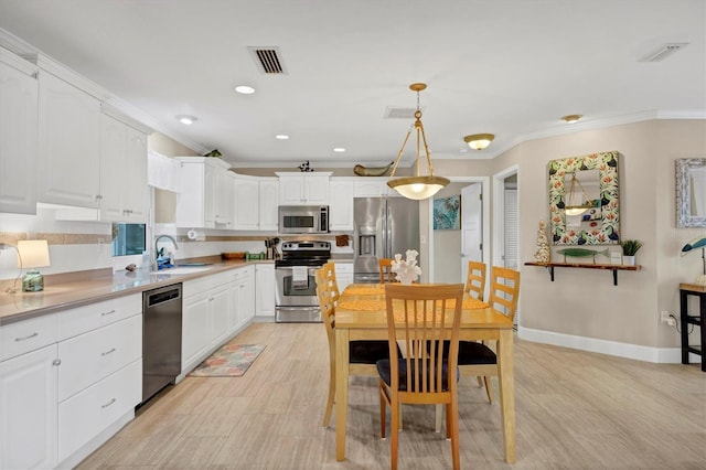 kitchen with white cabinetry, sink, pendant lighting, and appliances with stainless steel finishes