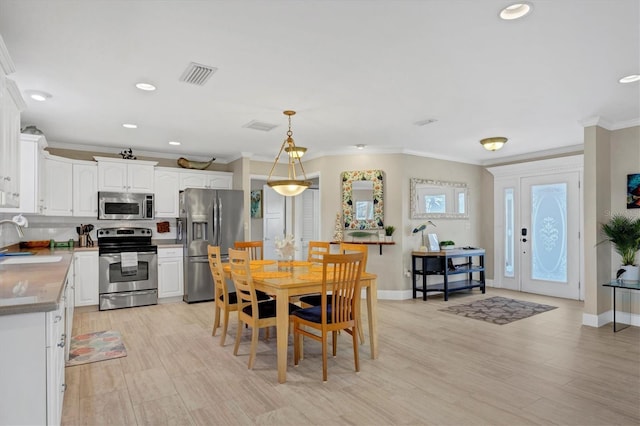 dining space featuring light hardwood / wood-style floors, sink, and ornamental molding