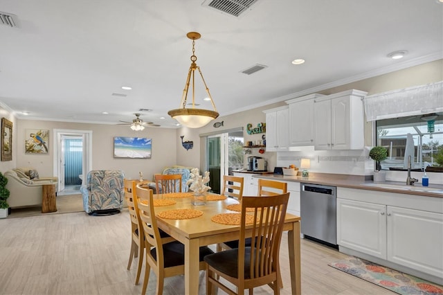 dining area with ceiling fan, sink, plenty of natural light, and crown molding