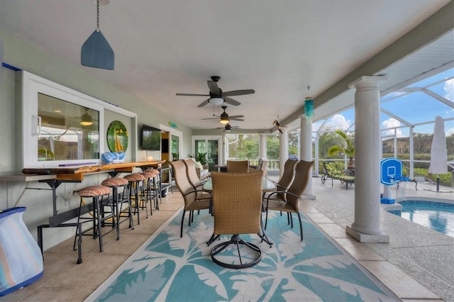 view of patio / terrace featuring ceiling fan, glass enclosure, and an outdoor bar