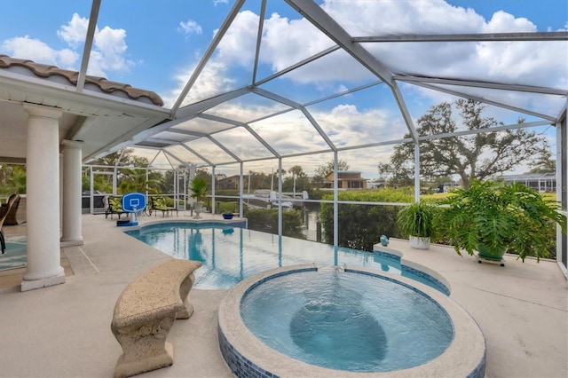 view of pool featuring a patio, glass enclosure, and an in ground hot tub