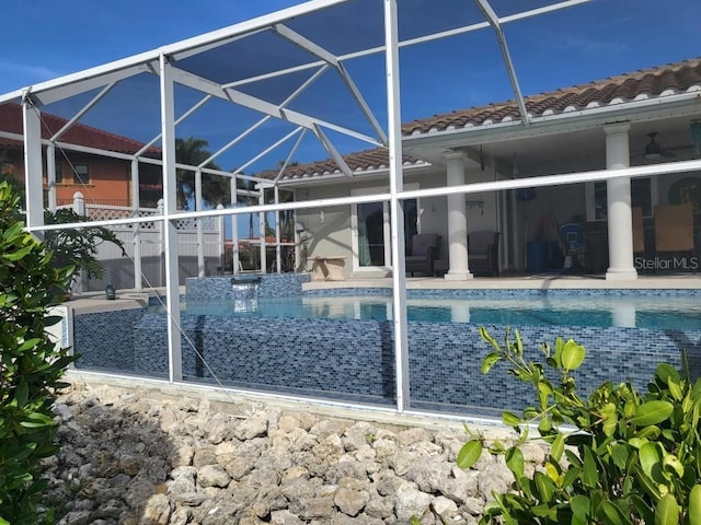 view of pool with glass enclosure and a patio area