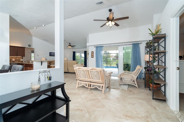 living room featuring a textured ceiling, ceiling fan, and lofted ceiling