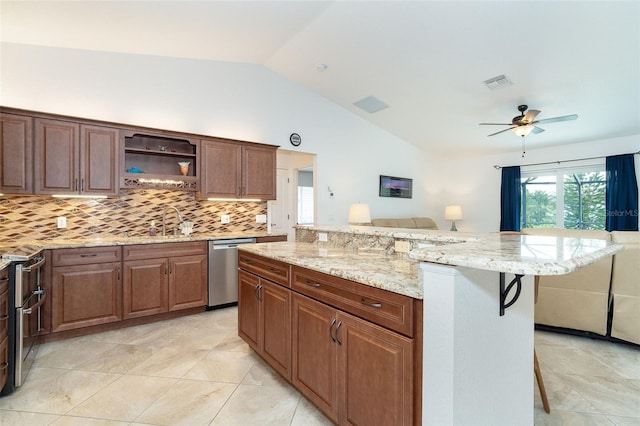 kitchen featuring appliances with stainless steel finishes, lofted ceiling, backsplash, ceiling fan, and a breakfast bar area