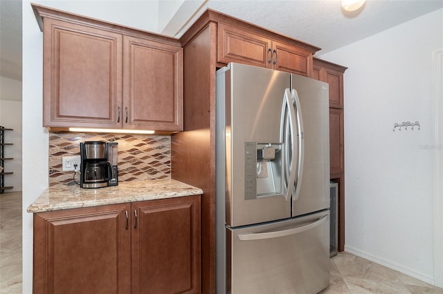 kitchen with light stone counters, light tile patterned flooring, stainless steel fridge with ice dispenser, and tasteful backsplash